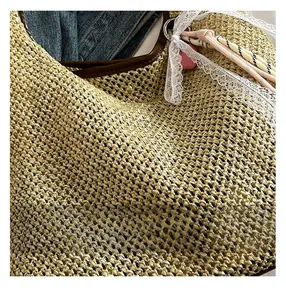 Detail of handwoven straw tote featuring delicate lace ribbon and colorful rope pendant