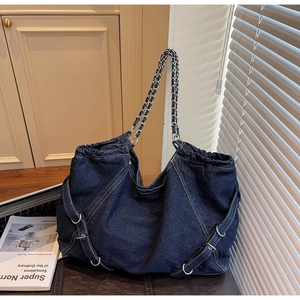 Detail of dark blue denim tote bag with silver chain strap and cross stitching decoration