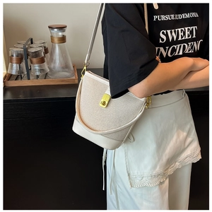 Detailed close-up of white mesh and leather bucket bag featuring a gold clasp buckle