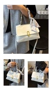 Detail of cream crossbody bag featuring woven texture and decorative silk scarf handle