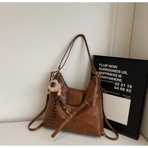 Close-up of caramel leather tote bag showing smooth texture and plush lion pendant