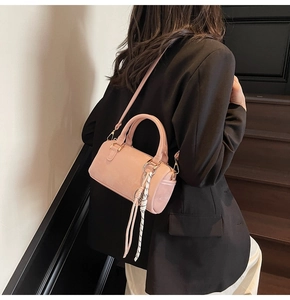 Detail of pink Boston bag showing smooth matte texture, ribbon charm and gold hardware