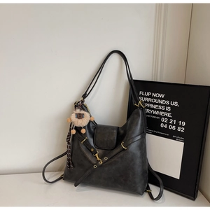 Detail view of large dark grey hobo bag with metal buckles and a cute sheep plush charm