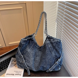 Close-up of blue washed denim tote bag with metal chain strap and retro hardware
