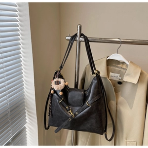 Detail of black tote bag featuring vintage texture, gold hardware and plush charm