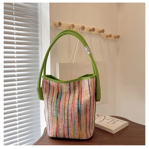 Detailed view of colorful striped bucket bag with vibrant green leather handles