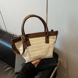 Dettaglio della borsa mare intrecciata beige con finiture in pelle marrone e doppi manici