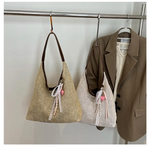 Detailed view of woven straw hobo bags with leather handles and lace bow accents
