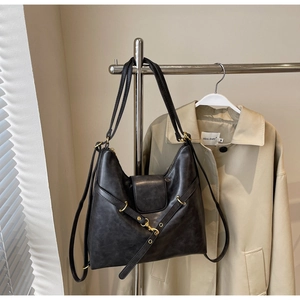 Detail of vintage black leather tote bag with gold metal buckle and textured finish