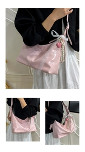 Detailansicht der rosa Lacklederhandtasche mit weißem Spitzenbesatz und Herzanhänger