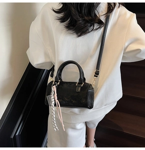 Detail view of a black Boston bag with matte leather texture and gold-tone zippers