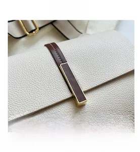 Détail du fermoir métallique doré sur le sac en cuir beige à grain de litchi