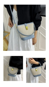 Detailed view of beige canvas bucket bag with light blue leather trim and golden metal clasp
