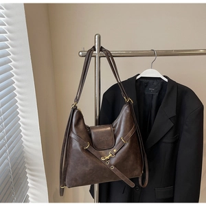 Detail of vintage dark brown faux leather tote with golden hook on metal display rack