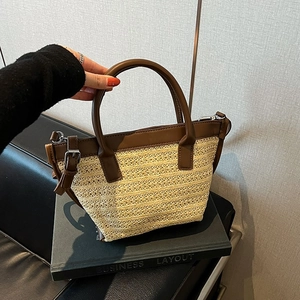 Dettaglio borsa tote in paglia intrecciata con finiture in pelle marrone e tracolla regolabile