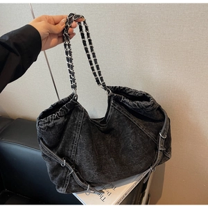 Detail of black denim tote bag with silver chain strap and drawstring closure design