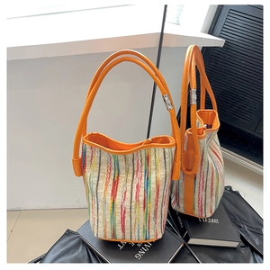 Detailed view of colorful striped woven bucket bag with orange handles and mirror reflection