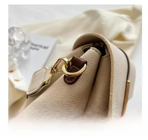 Détail du sac en cuir grainé avec boucle en métal doré et bordure en cuir marron