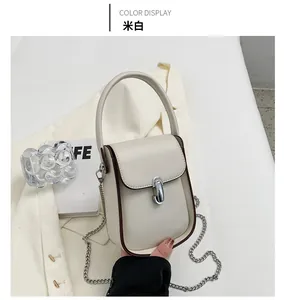 Κοντινό πλάνο κρεμ μίνι τσάντας χιαστί με ασημένιο κλείδωμα πάνω σε λευκό κοστούμι