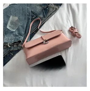Sac baguette rose avec boucle argentée en G et double bandoulière sur lit blanc
