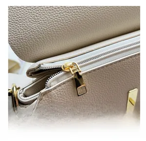Détail de la fermeture éclair en métal doré et de la texture du cuir sur le sac crème