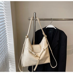 Detail of cream leather tote bag featuring gold hardware and fashion brand lettering