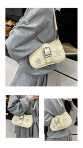 Detail of a chic cream underarm bag with star-shaped quilting and a metal buckle