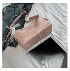 Detail der rosa Umhängetasche mit Spitzenschleifen und Herzanhänger auf Stoff