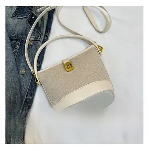 Detail view showing cream canvas and leather bucket bag with gold twist lock and strap