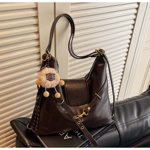 Detail of a dark brown large tote bag featuring a cute lamb charm and soft leather texture