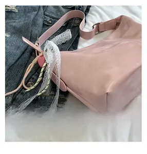 Detailansicht der rosa Ledertasche mit Spitzenbesatz und Webband auf einer Denim-Jacke