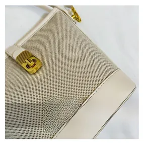 Close-up of beige woven mesh fabric with smooth leather trim and golden metal turn lock clasp