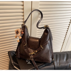 Detail of dark brown tote bag showing gold hardware, PU leather texture, and plush bear charm