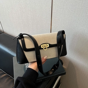Minimalist beige canvas baguette shoulder bag with black leather trim and gold hardware