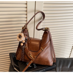 Macro detail of brown leather tote bag showing plush lion charm and fine stitching