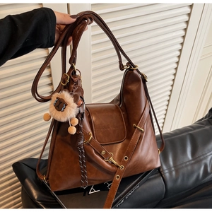 Detail view of brown vintage tote bag with soft leather texture and plush sheep charm