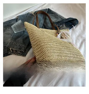 Detailed macro view of woven straw beach tote bag with brown leather handles and lace charm
