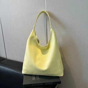 Detailed texture of yellow lychee grain leather tote bag on minimalist background