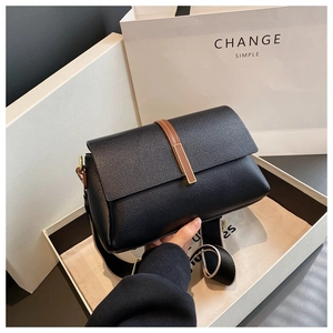 Détail d'un sac bandoulière en cuir grainé noir avec une large bandoulière en tissu