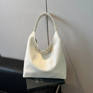 Detail of the wide shoulder strap and leather buckle on this cream textured hobo bag