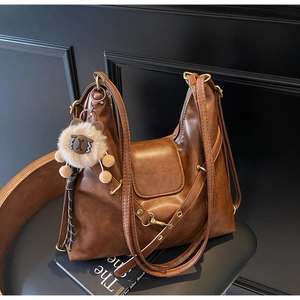 Detail of vintage brown textured leather tote with antique hardware and lion plush charm