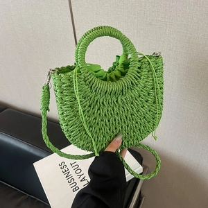 Detail of light green straw handbag with circular handle and detachable shoulder strap
