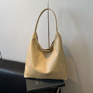 Macro view of textured lychee pattern leather and soft structure of the beige hobo tote bag