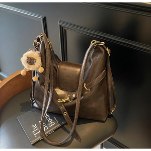 Detailed view of deep brown vintage tote bag with gold hardware and lion charm