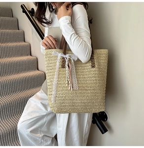 Close-up of woven tote bag with white lace bow and colorful stripe charm detail