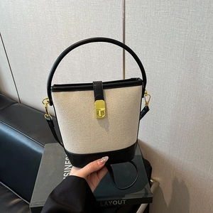 Fashionable canvas and black leather bucket bag with top handle and metal clasp closure