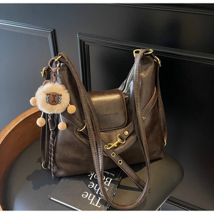 Detail of dark brown faux leather tote bag with vintage texture and plush sheep charm