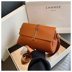 Détail du sac bandoulière en cuir grainé marron avec large sangle tissée et boucle dorée