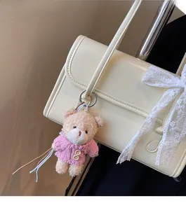 Détail d'un porte-clés ours en peluche crème avec gilet rose sur un sac à main
