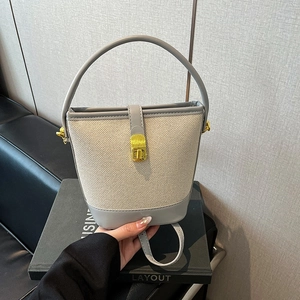 Detail of canvas bucket bag with grey faux leather trim and gold metal lock closure